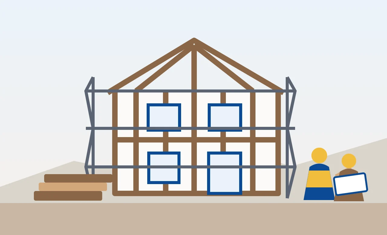 Two-story house frame under construction with scaffolding, stacked materials, and workers reviewing the build